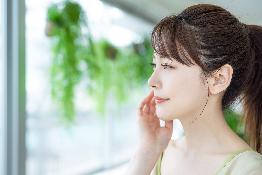 頬を気にしながら遠くを見つめる女性